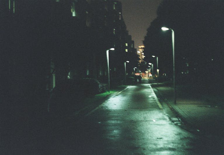 Dimly lit urban alley at night with glowing streetlights casting a mysterious ambiance.